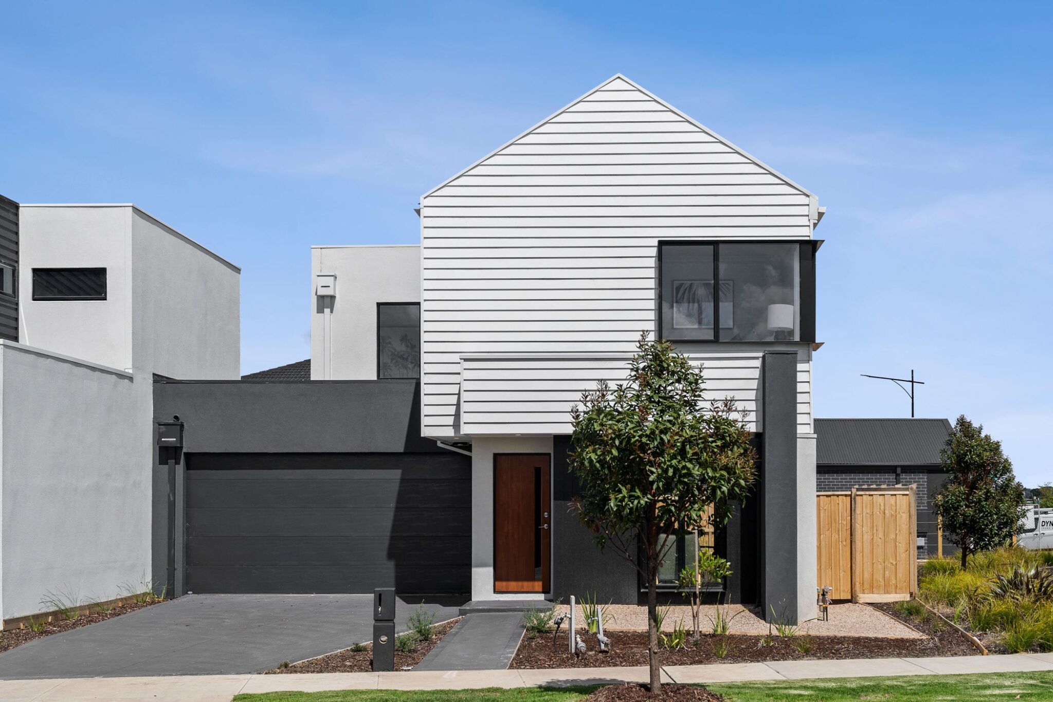 Image of white townhome with double garage, porch, tree and blue sky